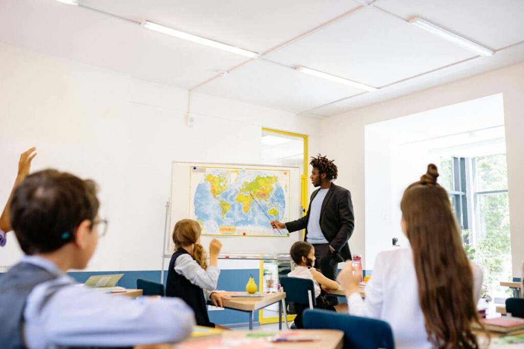 An educator pointing to a large, AI-powered interactive screen in a modern classroom setting.