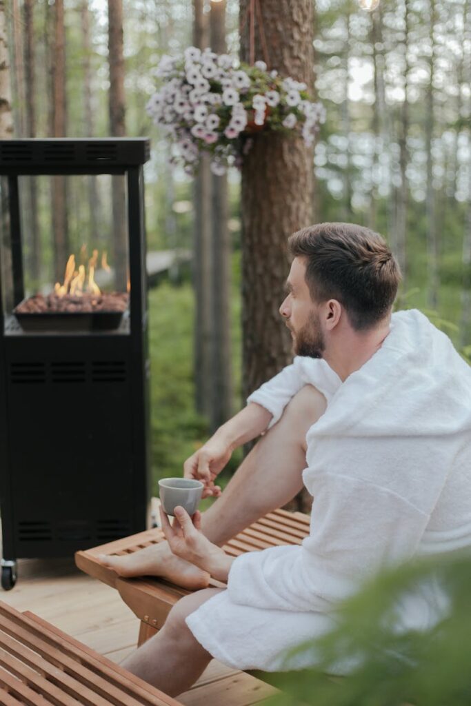 A group of people sit in a meditative lotus pose on wooden platforms in a lush, green forest, finding peace and quiet during a yoga retreat.