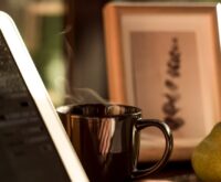 A writer's desk with an open laptop, a notebook, and a cup of coffee, symbolizing the ebook creation process.