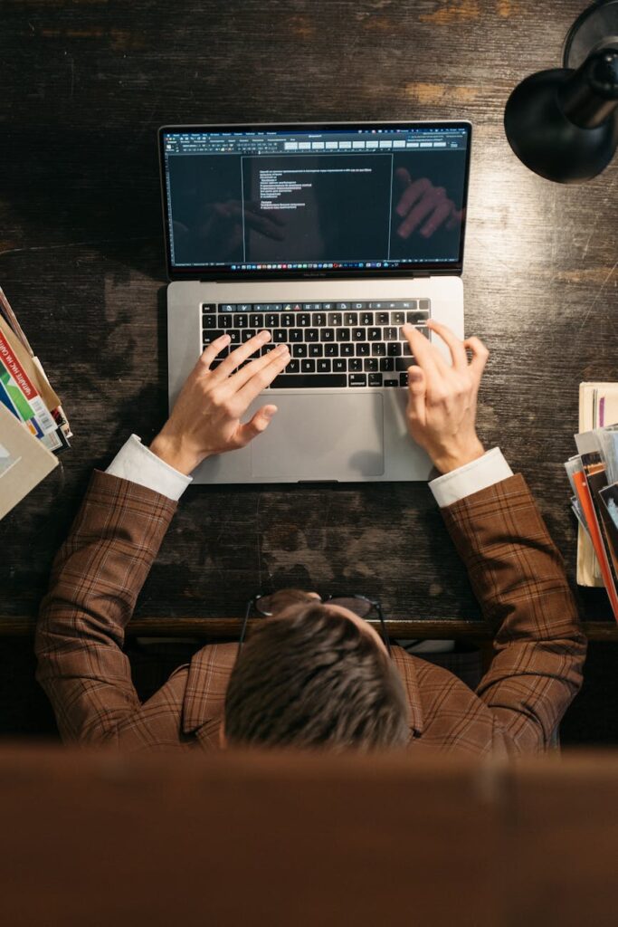 A focused individual at a desk using a laptop to learn about AI and coding.