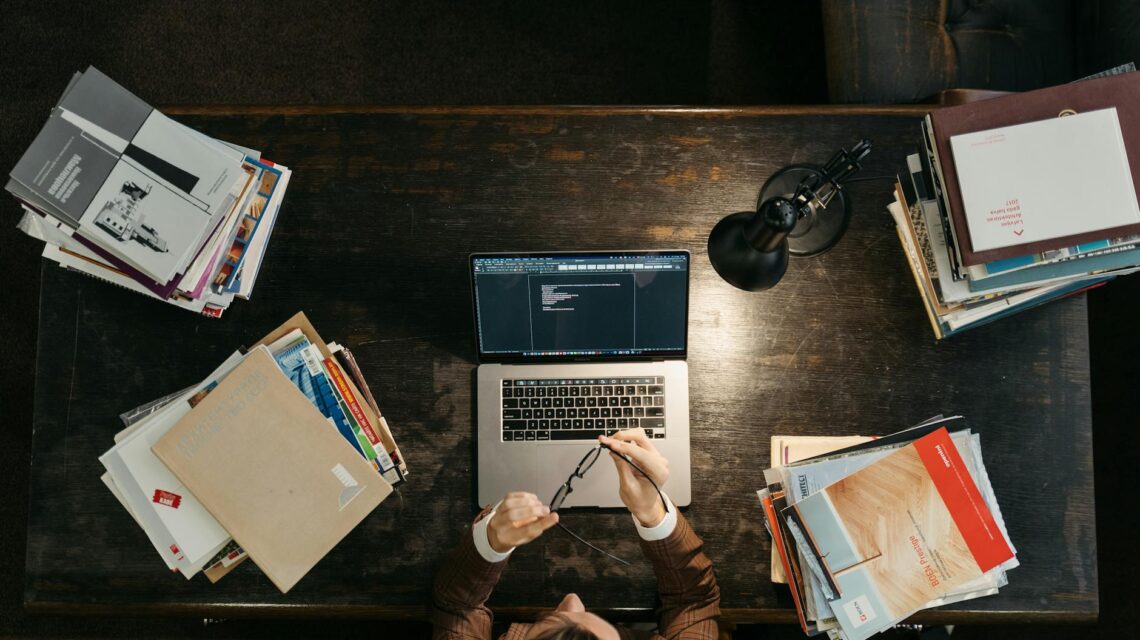 A software developer types on a laptop, with glowing lines representing an AI neural network superimposed over the image.