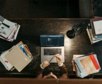 A software developer types on a laptop, with glowing lines representing an AI neural network superimposed over the image.