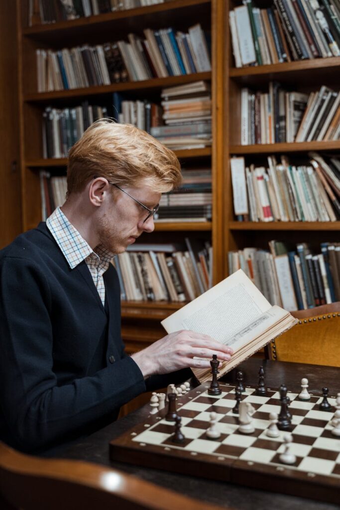 A person sitting in a rustic wooden cabin, deeply engrossed in a book with a forest visible through the window.
