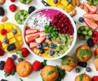 A beautifully arranged platter featuring salmon fillets, a bowl of mixed berries, walnuts, and spinach, representing foods that reduce inflammation.