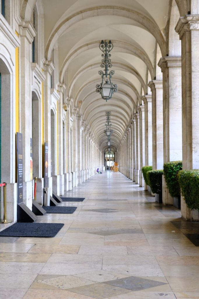 A lone traveler with a backpack stands in awe, looking up at the ornate balconies and red velvet seats of an empty European opera house.