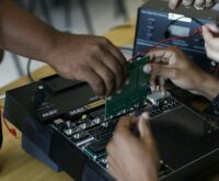 A group of diverse university students working together on an electronics project in a brightly lit laboratory.