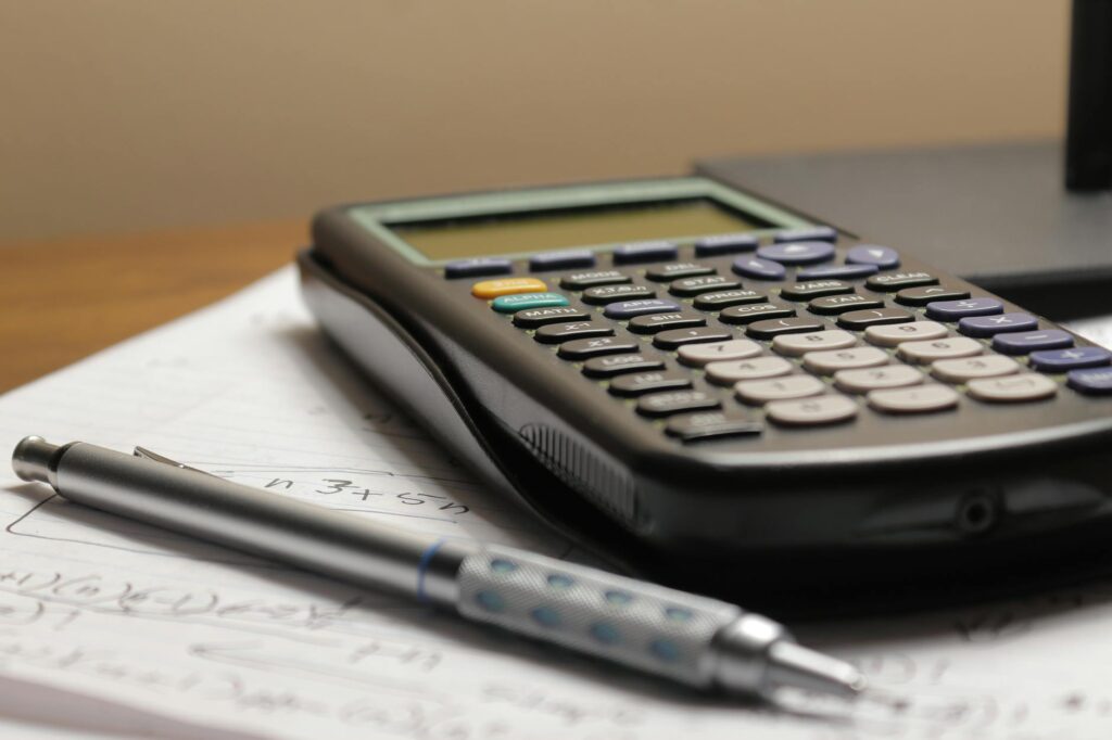 A detailed view of a calculator, pen, and papers with financial metrics like LTV and CAC.