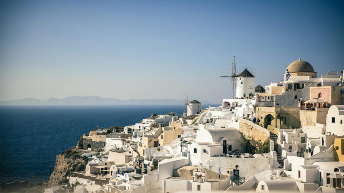 A wide-angle view of the iconic Santorini sunset with orange and pink hues over the white-washed buildings of Oia.