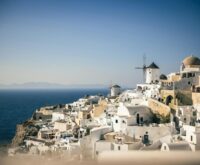 A wide-angle view of the iconic Santorini sunset with orange and pink hues over the white-washed buildings of Oia.