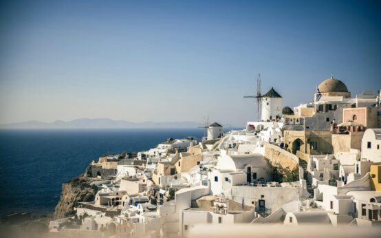 A wide-angle view of the iconic Santorini sunset with orange and pink hues over the white-washed buildings of Oia.