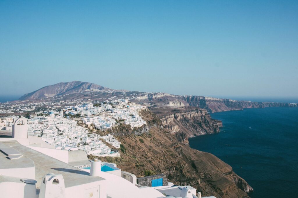 A panoramic shot of the volcanic caldera in Santorini as the last light of the sun casts a purple glow on the sea.