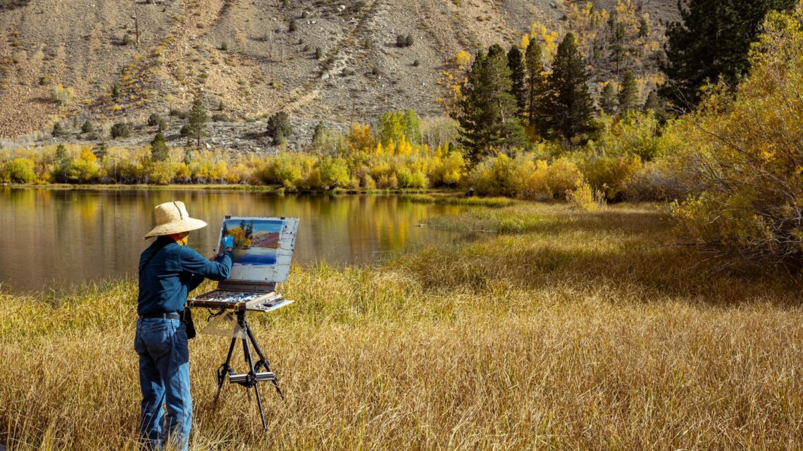 An artist with an easel painting a vibrant purple lavender field in Provence, France.