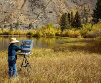 An artist with an easel painting a vibrant purple lavender field in Provence, France.