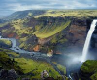 The iconic Múlafossur waterfall cascading over a dramatic cliff into the Atlantic Ocean in the Faroe Islands.