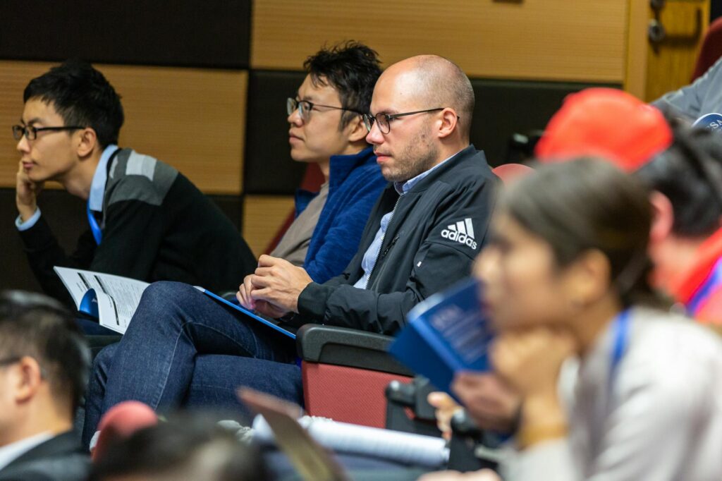 A wide shot of a lecture hall with a diverse group of attentive students looking towards the professor.