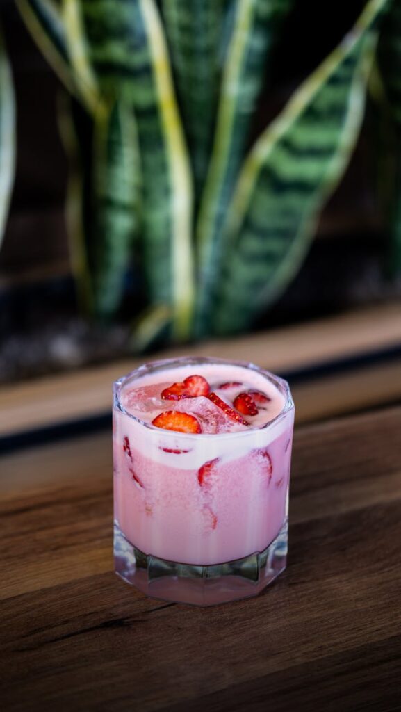 A detailed shot of a glass of mojito with mint and lime, with a pair of casual sandals blurred in the background.