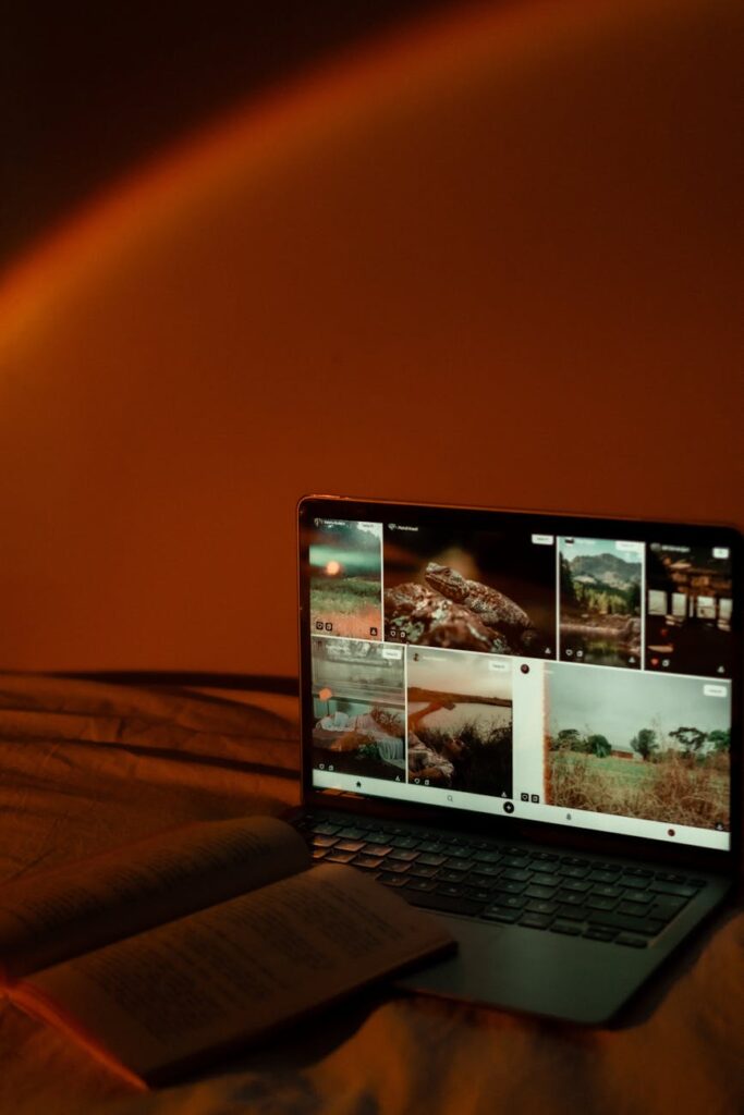 A focused student wearing headphones studies intently in a dark library, illuminated by their laptop.