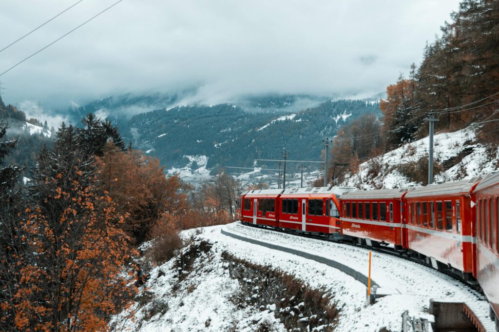 A long passenger train curving along a track through a lush, scenic valley during the day.