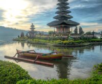 A lone hiker watches the sunrise over a calm, misty mountain range.