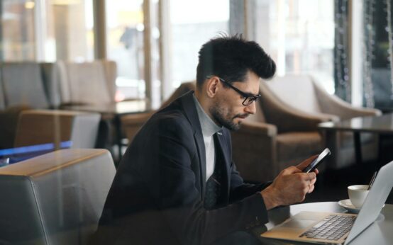A person pointing their smartphone at their living room floor, with an augmented reality projection of a new armchair appearing on the screen.