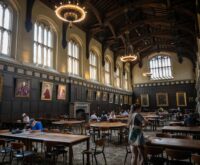 A university student carefully examining an ancient manuscript in a well-lit library.
