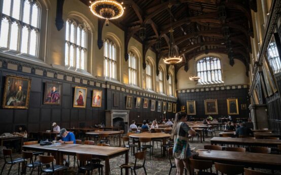 A university student carefully examining an ancient manuscript in a well-lit library.