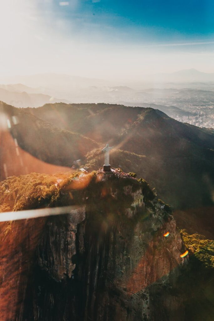 A lone traveler with a backpack looks out over a majestic mountain range at sunrise.