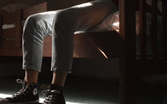 Close-up of a person's feet dangling in a blue swimming pool next to a colorful summer cocktail.