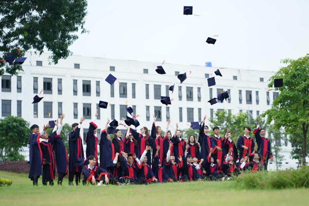 A joyful crowd of graduates in gowns toss their caps into the blue sky during a commencement ceremony.