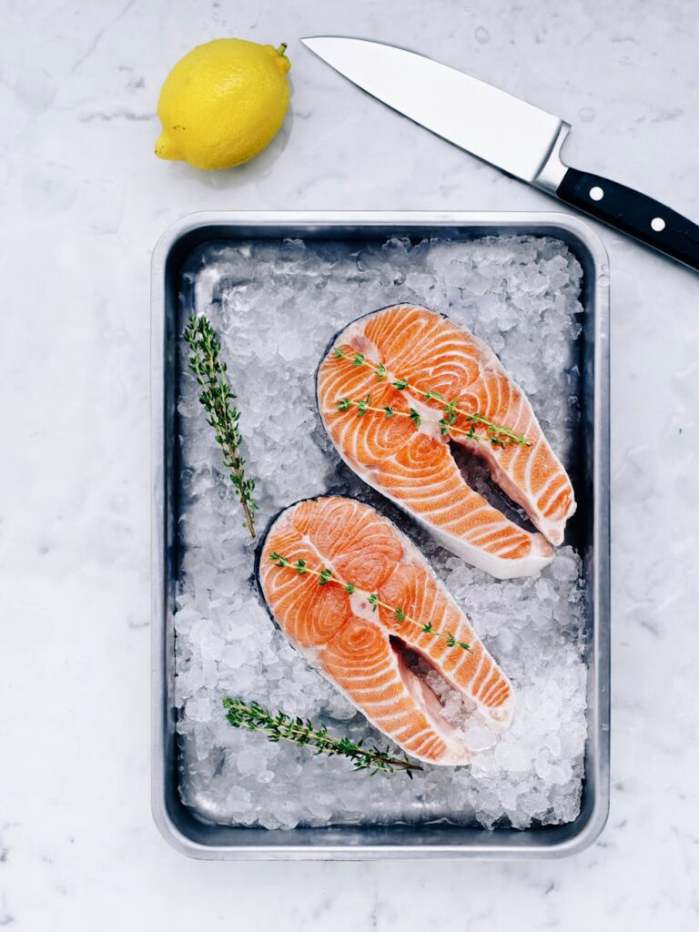 A perfectly grilled salmon fillet garnished with fresh dill and lemon slices on a dark plate.