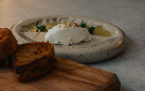 A freshly baked loaf of gluten-free bread sitting on a rustic wooden cutting board, ready to be sliced.