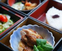 Top-down view of several glass meal prep containers filled with grilled chicken, quinoa, and roasted broccoli.