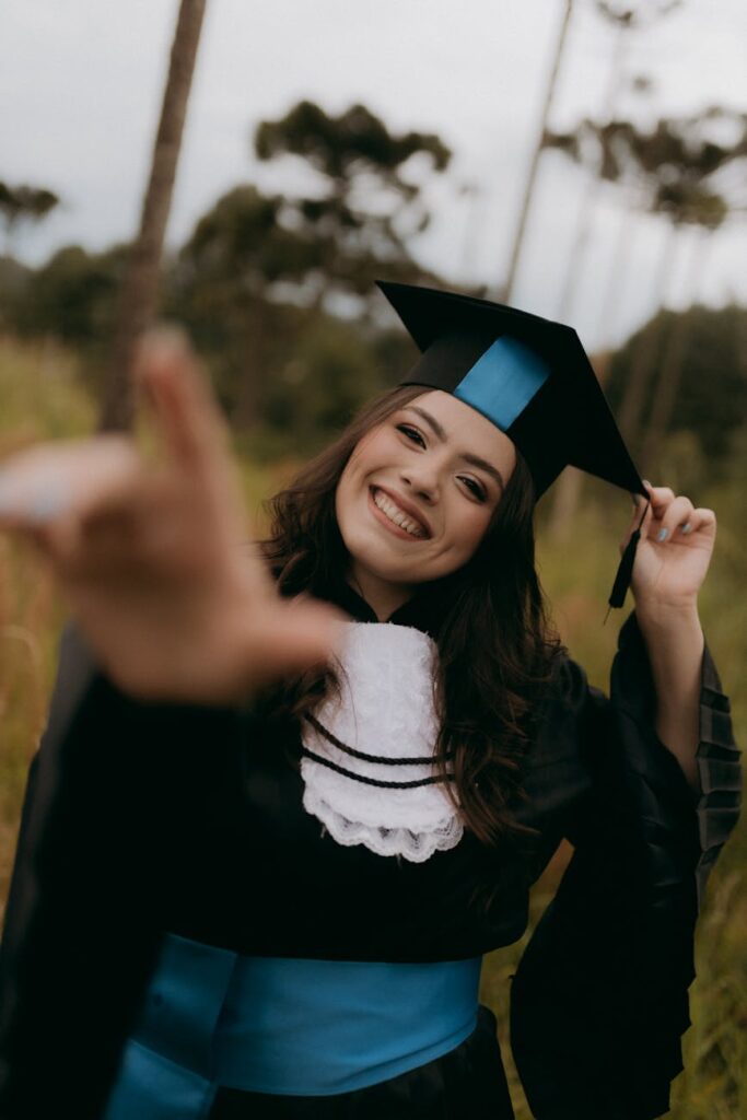 A recent graduate in a cap and gown tosses their cap, their facial expression a mix of happiness and uncertainty about the future.