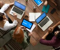 Two business professionals shaking hands across a meeting room table after a successful negotiation.