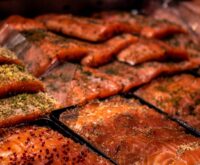 A vibrant array of colorful spices displayed in woven baskets at a crowded outdoor market.