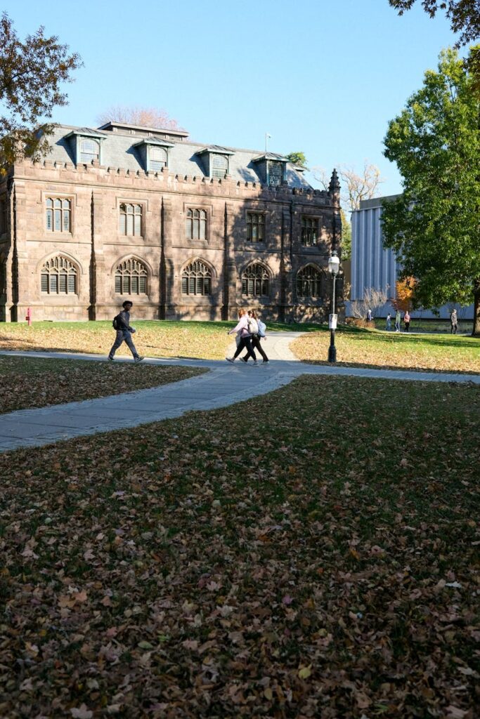 A group of young, happy students walking together with backpacks on a sunny college campus path.