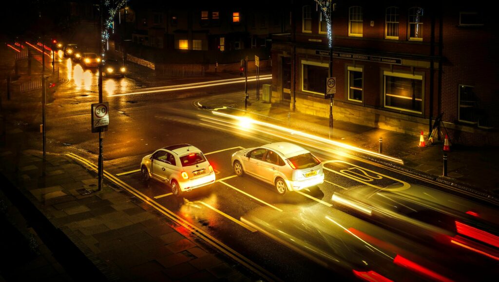A vibrant, long-exposure photograph of the Shibuya crossing in Tokyo at night, with light trails from cars and people.