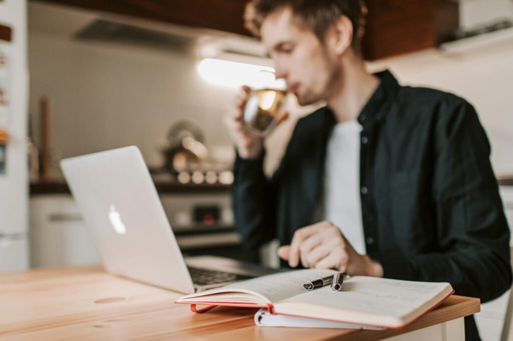 A concerned-looking student sits in front of a laptop, deep in thought while searching for jobs online.