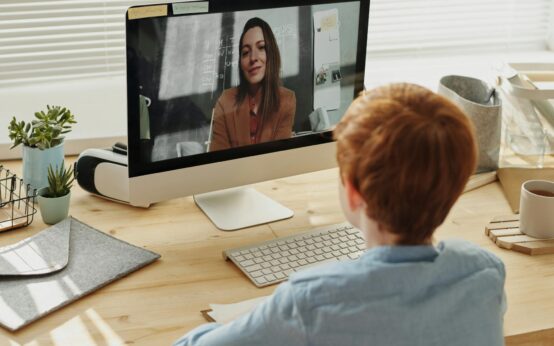 A diverse group of students sitting at desks in a bright classroom, each focused on their laptop.