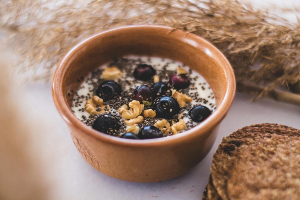 A ceramic bowl filled with a healthy mix of walnuts, almonds, and chia seeds, foods rich in omega-3s.
