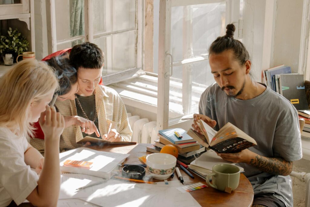 Four diverse university students smiling and pointing at a laptop screen during a collaborative study session.