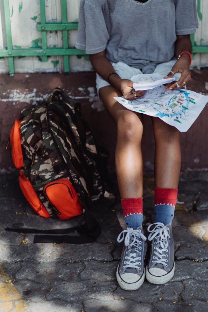 A young student with a backpack consults a paper map in a historic European city street.