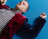 A person's feet propped up on a poolside chair next to a vibrant red smoothie.