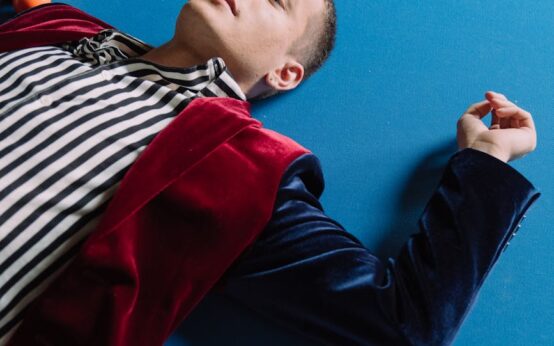 A person's feet propped up on a poolside chair next to a vibrant red smoothie.