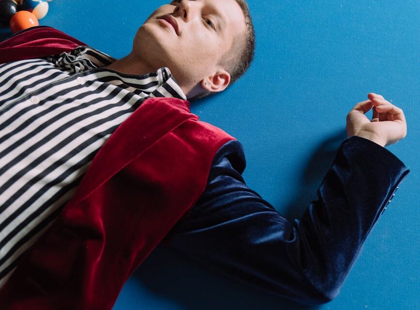 A person's feet propped up on a poolside chair next to a vibrant red smoothie.