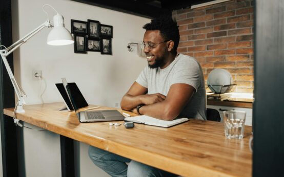 A university student sitting at a desk with a laptop, tutoring online from their dorm room.