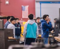A diverse group of engaged high school students working together around a table in a bright, modern classroom.