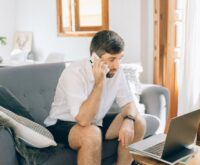 A commuter plans their trip on a smartphone while riding a train, with scenic countryside visible through the window.