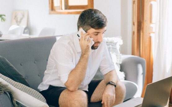 A commuter plans their trip on a smartphone while riding a train, with scenic countryside visible through the window.