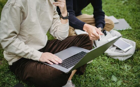 A diverse group of university students gathered around a laptop, working together on a complex tech project.